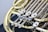 A close-up view of a brass musical instrument, specifically a French horn, highlighting the intricate valves and tubing. The metal parts are polished and shiny, reflecting light, with a focus on the keys and moving parts that control the instrument's pitch.