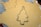 A metal Christmas tree-shaped cookie cutter is placed on rolled-out cookie dough alongside other cut-out tree shapes. The dough is laid on a surface with a mesh pattern visible in the background, and some flour is scattered around.