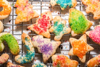 A collection of colorful baking extracts and M&M cookies cooling on a rack.