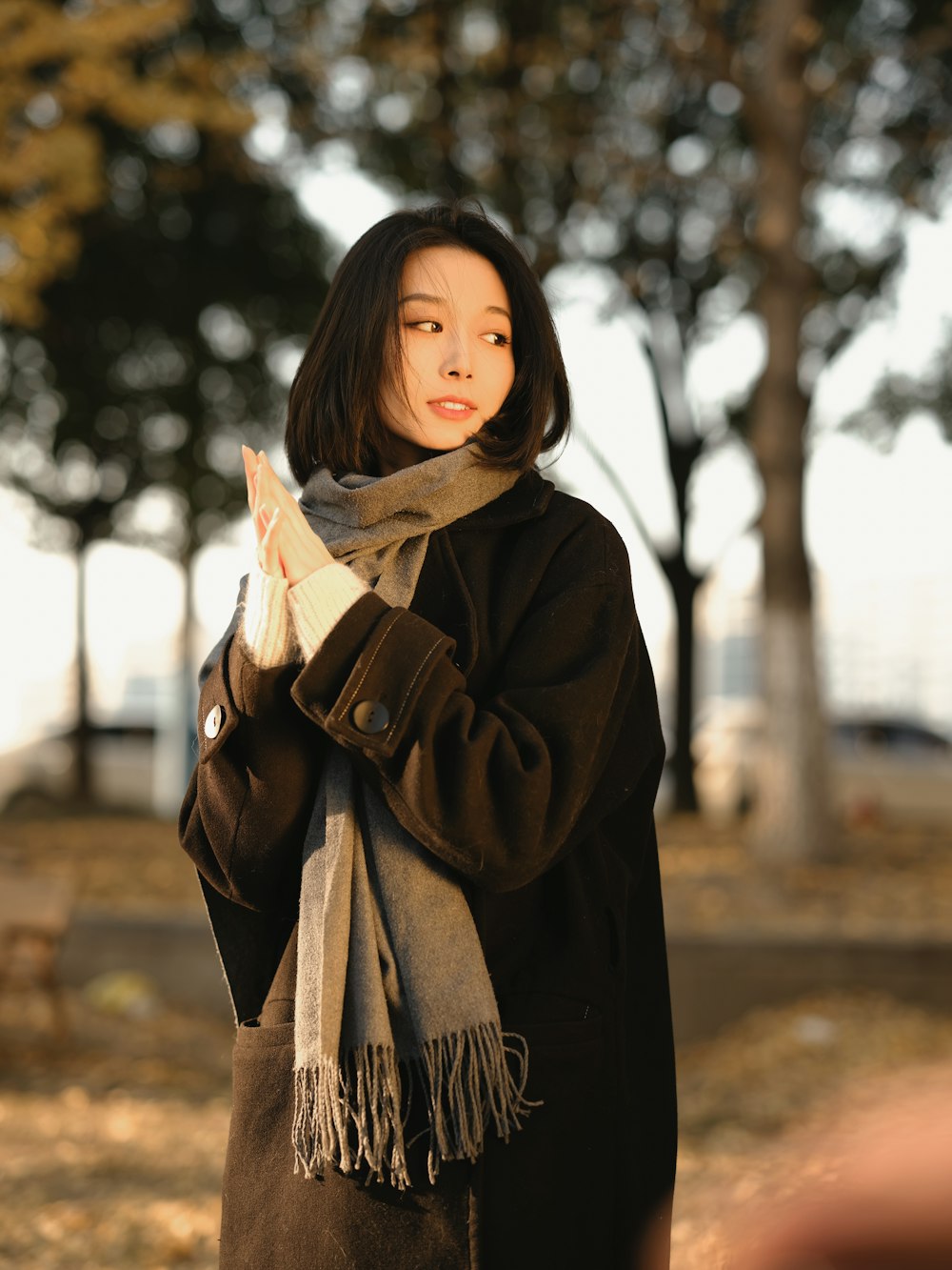 a woman standing in a park holding a cell phone