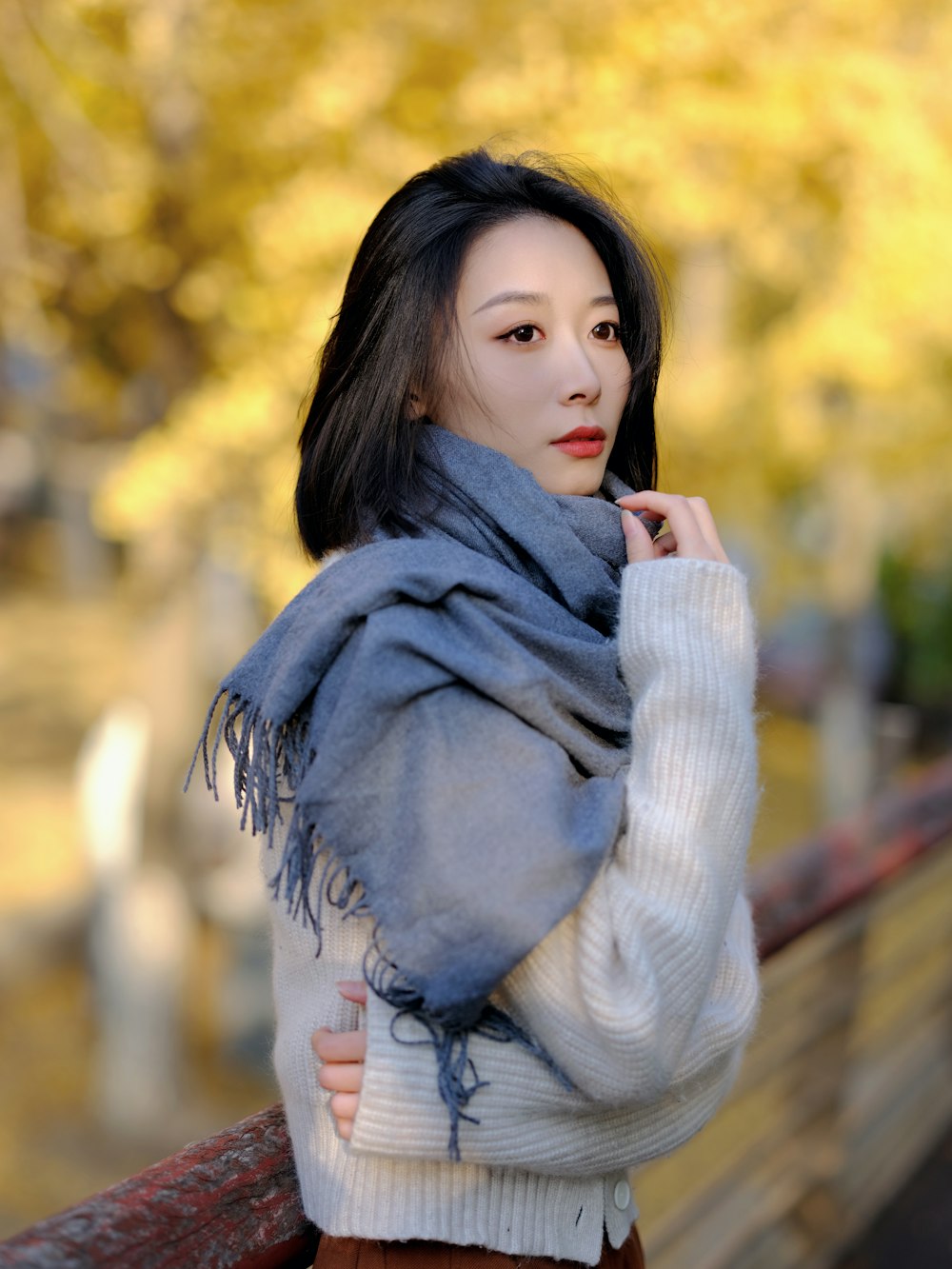 a woman standing on a wooden bench wearing a scarf