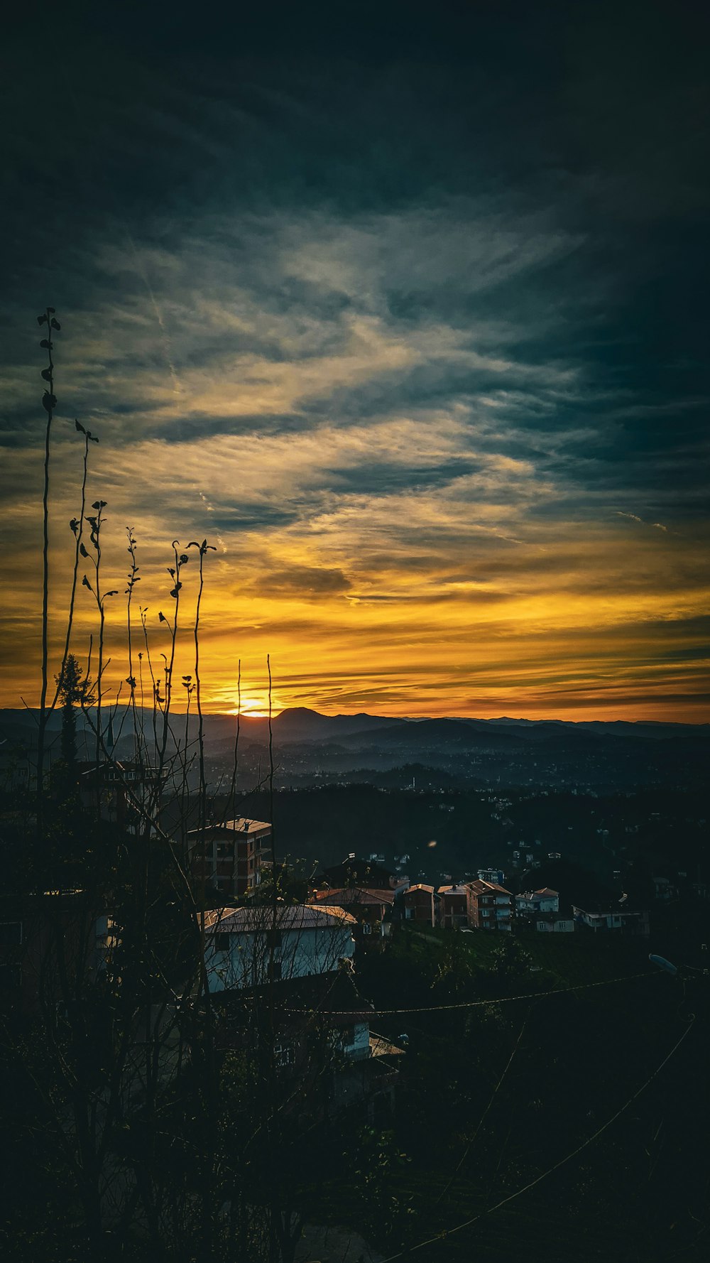 the sun is setting over a city and hills