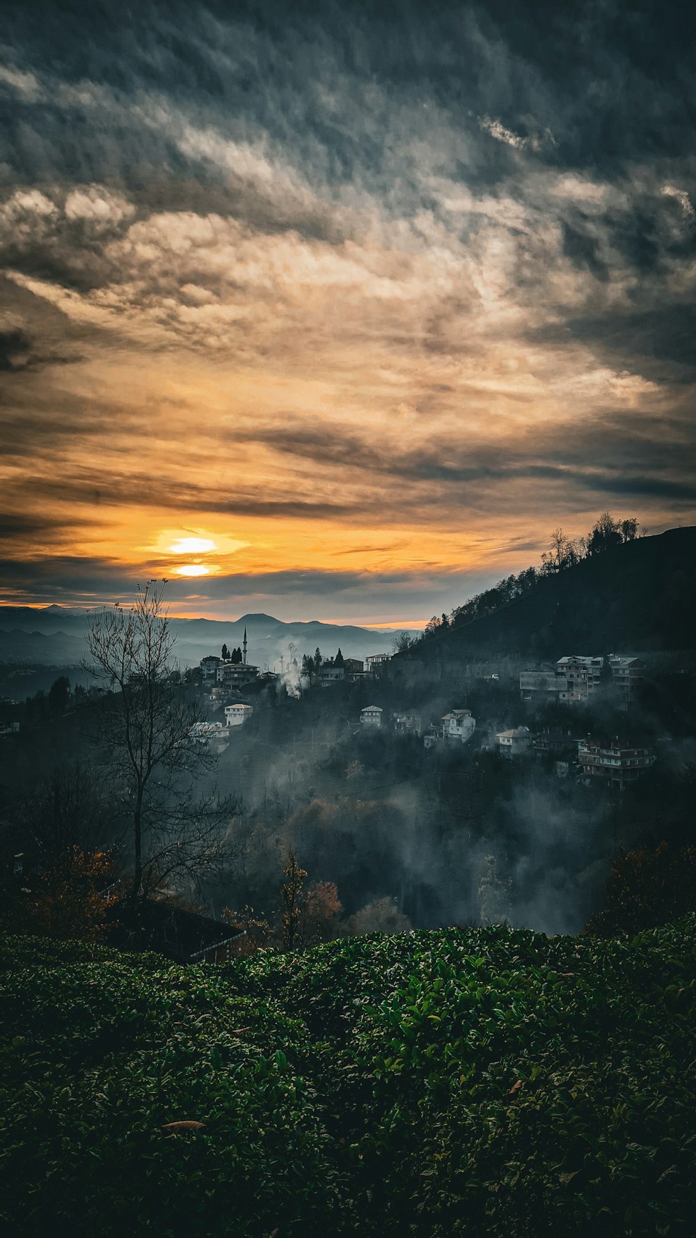 the sun is setting over a city with fog