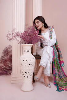A serene portrait of a woman in white sitting peacefully surrounded by soft natural light and delicate white flowers.