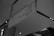 A monochrome photograph of a ceiling-mounted directional sign in a commercial or public space. The sign displays directions to various services including SEIBU, valet, premium concierge, and lifts A and E. The background shows part of a building interior with patterned walls and ceiling lights.