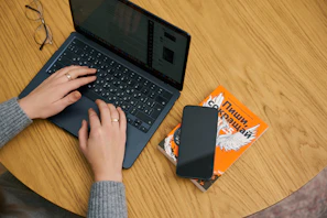 Close-up of Cory’s hands typing on a laptop with eBook drafts open.
