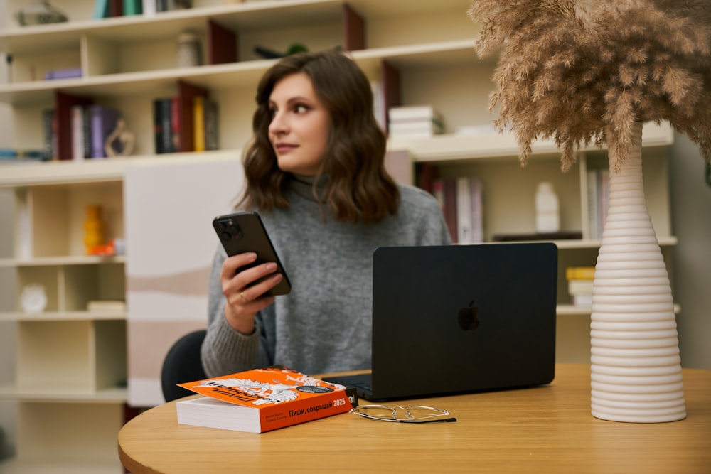 a woman sitting at a table looking at her phone