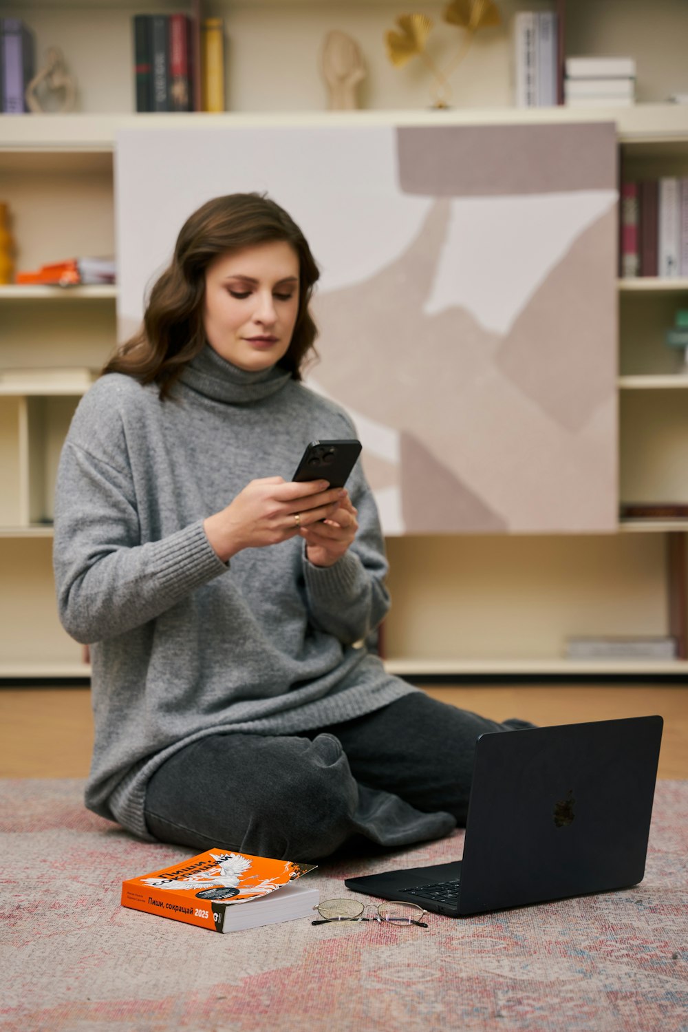 a woman sitting on the floor looking at her cell phone