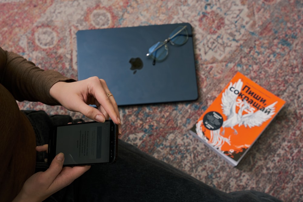 a person holding a smart phone next to a laptop