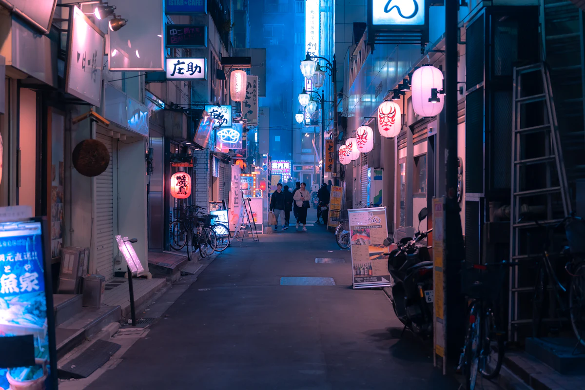 A narrow Tokyo city street at night lit up with neon signs