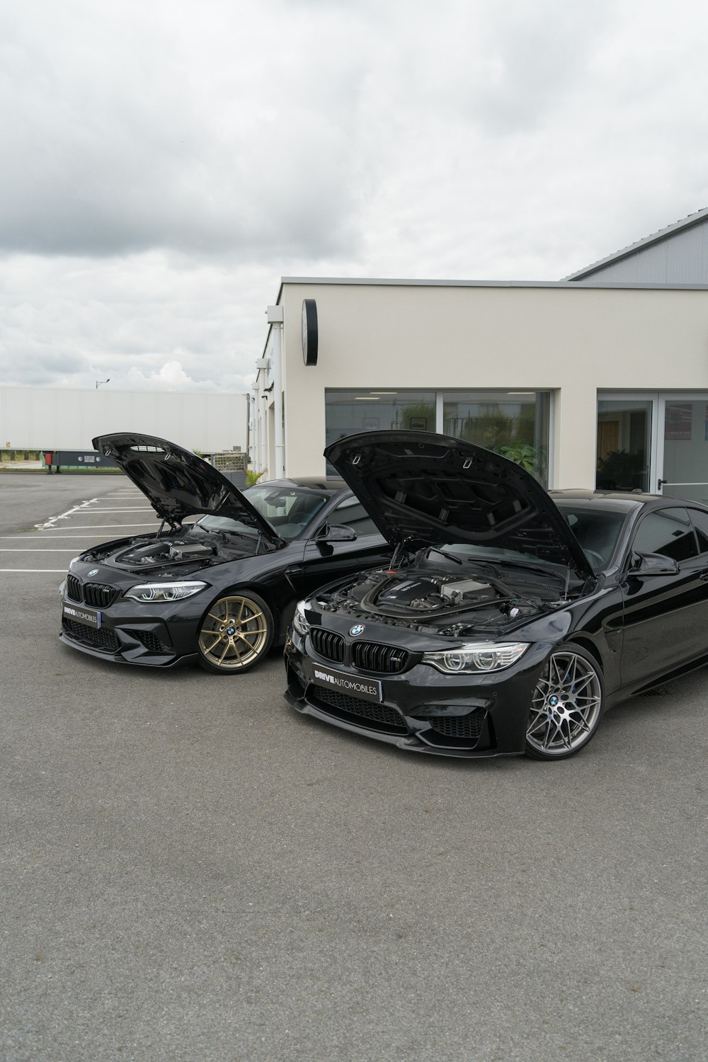 two cars parked in a parking lot with their hood open