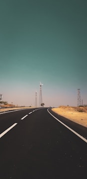 an empty road with windmills in the distance