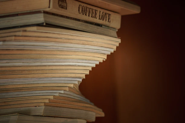 Stack of well-loved books with a cup of coffee on a wooden table.