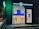 A pharmacy entrance with a large illuminated cross sign in blue and yellow colors. The signage above the door is in Cyrillic script, and there's a green neon cross on the building facade. Inside the well-lit store, shelves with products are visible.