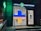 A pharmacy entrance with a large illuminated cross sign in blue and yellow colors. The signage above the door is in Cyrillic script, and there's a green neon cross on the building facade. Inside the well-lit store, shelves with products are visible.
