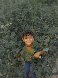 A child playing outdoors surrounded by greenery and natural elements