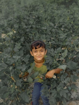 A child playing outdoors surrounded by greenery and natural elements