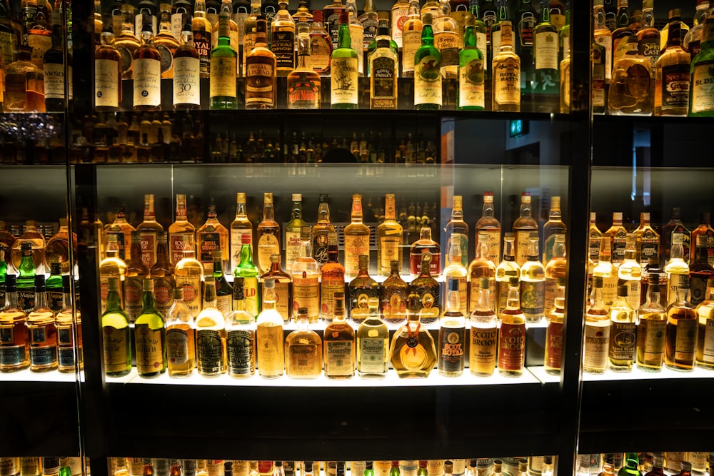 many bottles of alcohol are on display in a glass case