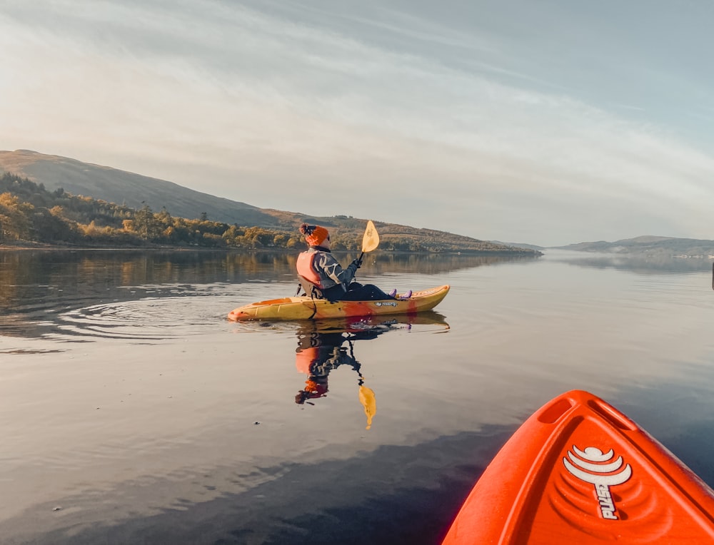 a man is paddling a kayak on a calm lake