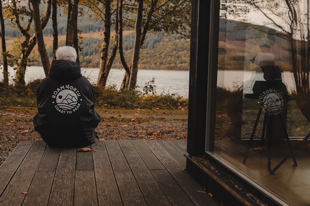 a person sitting on a deck looking out a window