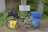 A touring bicycle is equipped with a variety of gear, including saddlebags and a handlebar bag. It is parked beside a multilingual sign indicating a watershed, surrounded by green vegetation and placed against a concrete structure.