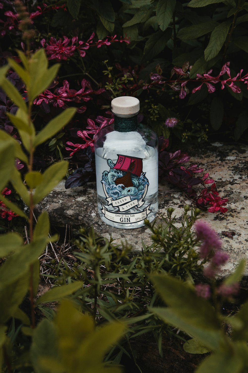 a bottle of water sitting in the middle of some flowers