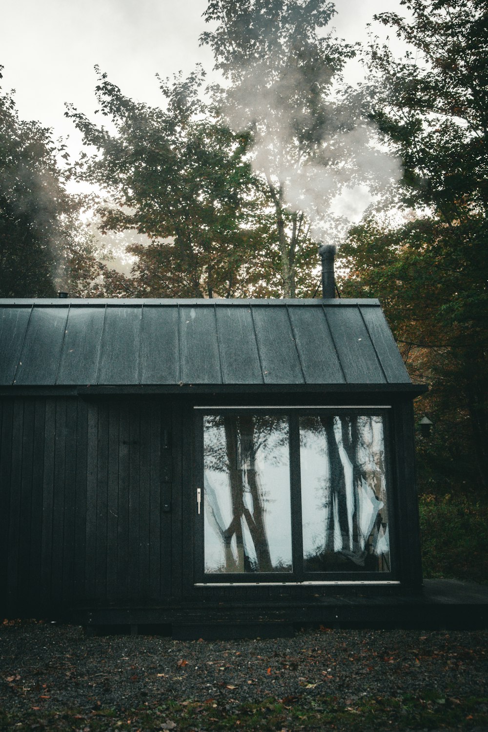 a black cabin with smoke coming out of the chimney