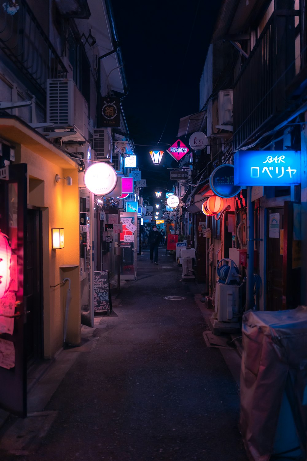 a narrow alley way with a neon sign on it