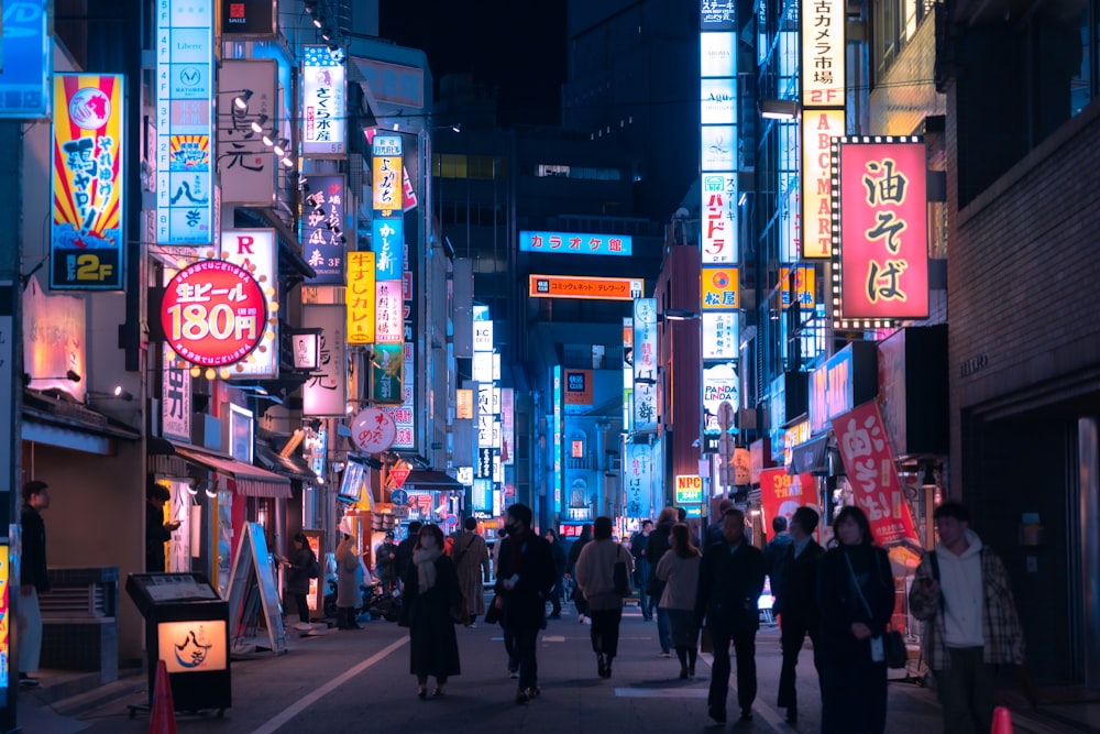 a group of people walking down a street at night