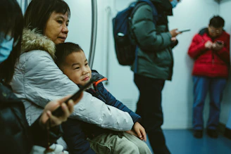 A smiling mother watching her child board the Kabu electric bus with a secure seatbelt.