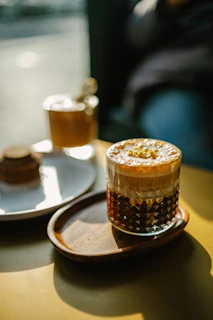 A close-up photo of a layered café-style drink with creamy milk and rich espresso in a clear glass.