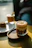 Close-up of a frothy coffee and colorful shake served on a glowing gold tray.