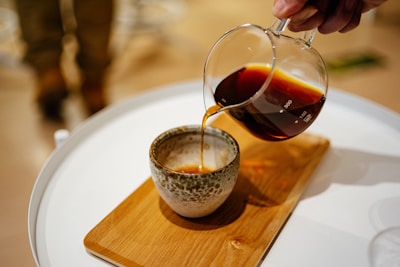 Close-up of a hand pouring freshly brewed coffee into a rustic mug.