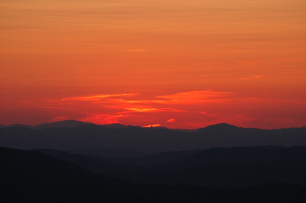 the sun is setting over the mountains in the distance