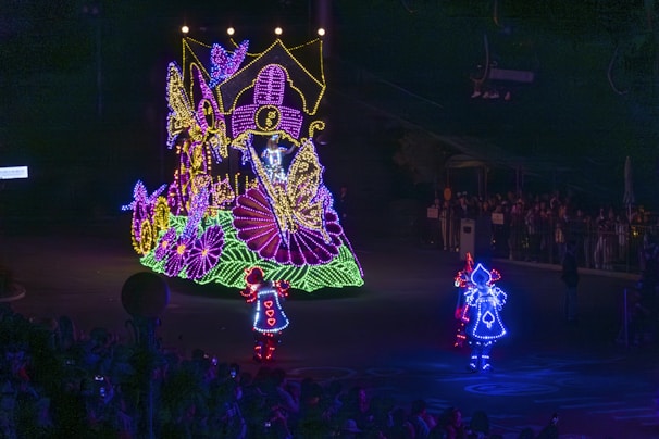 Nighttime scene with illuminated floats and joyful dancers celebrating Carnaval.