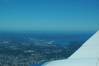 Aerial shot of a jet flying over a coastal landscape.