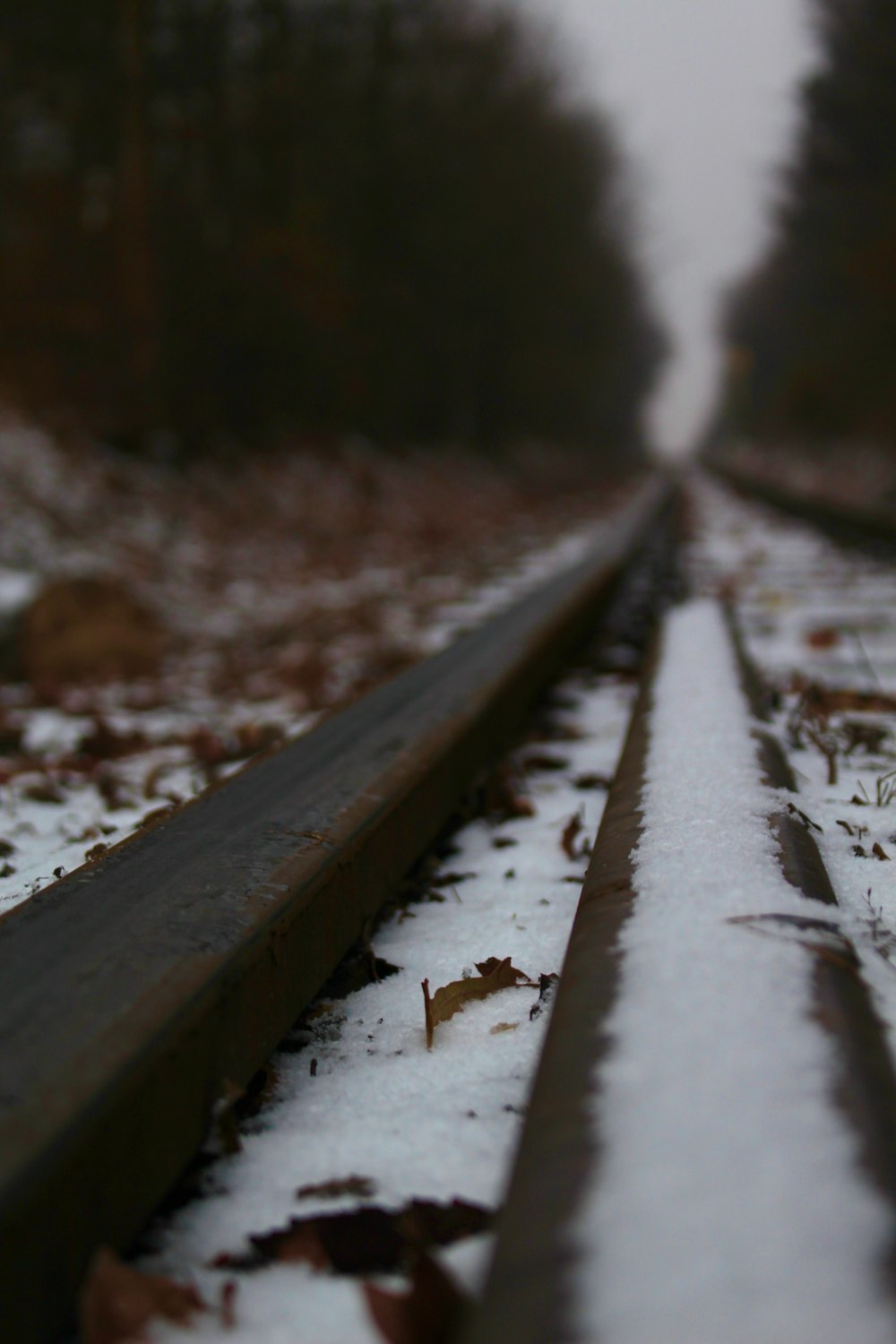a train track with snow on it and trees in the background