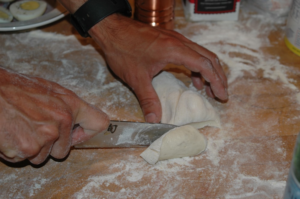 a person cutting dough with a knife on a table