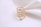 A gold ring with delicate floral designs encrusted with small diamonds, displayed on a soft white fabric background.