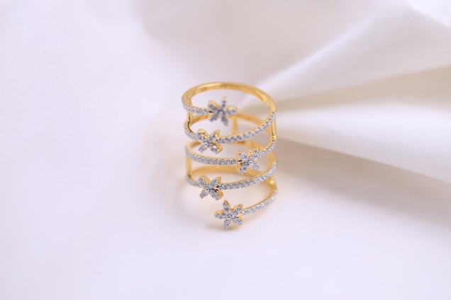 Close-up of a delicate, elegant gold ring with subtle diamonds on a soft off-white background.