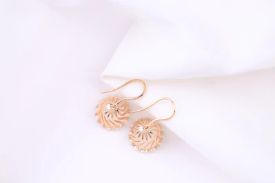 a pair of earrings sitting on top of a white cloth