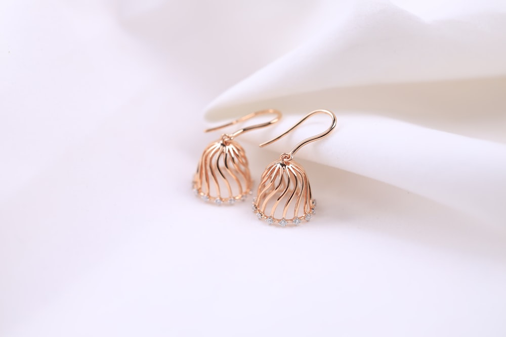 a pair of earrings sitting on top of a white cloth