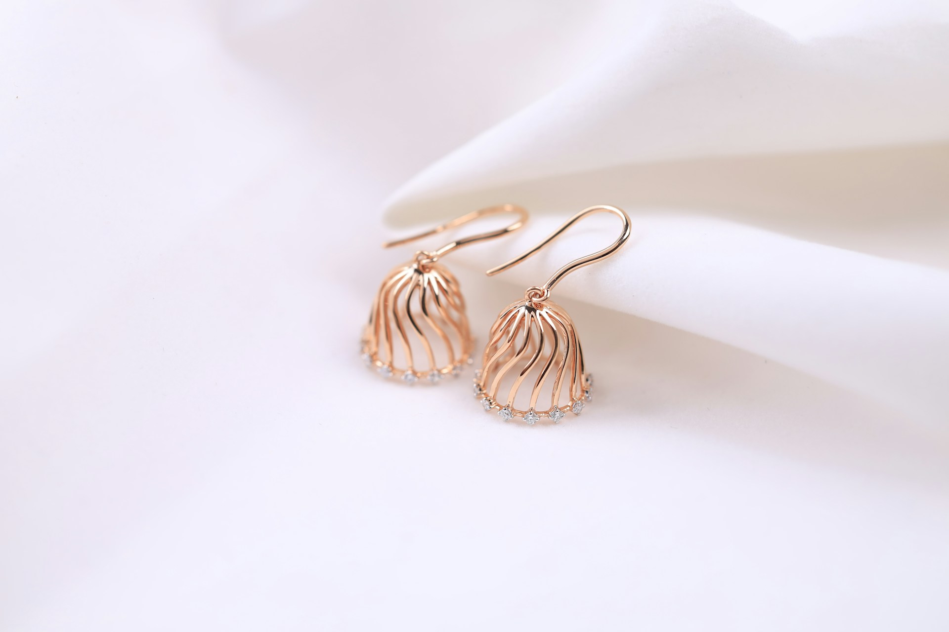 a pair of earrings sitting on top of a white cloth