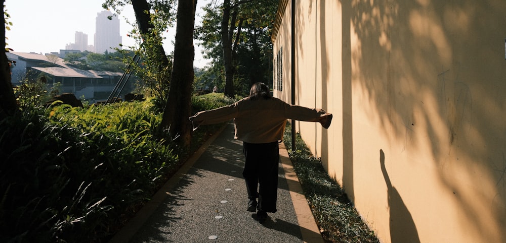 a man walking down a sidewalk next to a wall