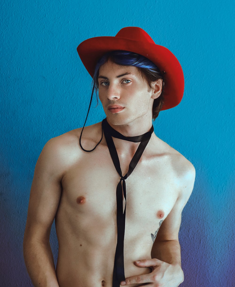 a shirtless man wearing a red hat and tie