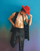 A lively model wearing a bright cowboy hat and colorful shirt against a rustic wooden backdrop.