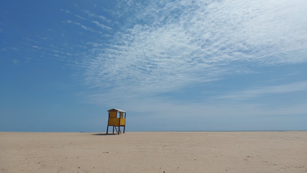 a yellow lifeguard chair sitting on top of a sandy beach