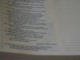 The image shows a close-up of a Bible page with text primarily from the book of Hosea. The page is slightly tilted, and the lighting creates shadows on the paper, emphasizing the printed words.