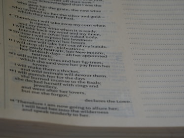 The image shows a close-up of a Bible page with text primarily from the book of Hosea. The page is slightly tilted, and the lighting creates shadows on the paper, emphasizing the printed words.
