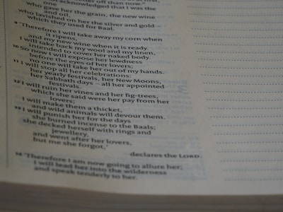 The image shows a close-up of a Bible page with text primarily from the book of Hosea. The page is slightly tilted, and the lighting creates shadows on the paper, emphasizing the printed words.